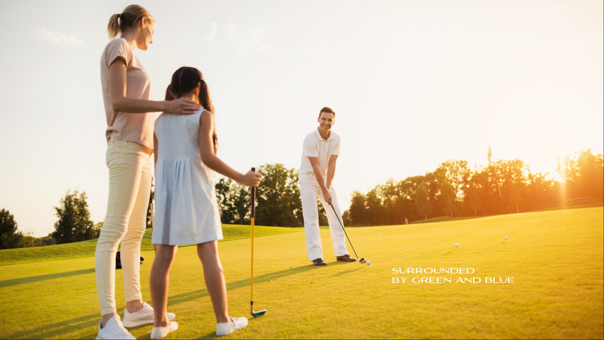 Father, mother and daughter playing golf at the sundown and the title 'Surrounded by green and blue'